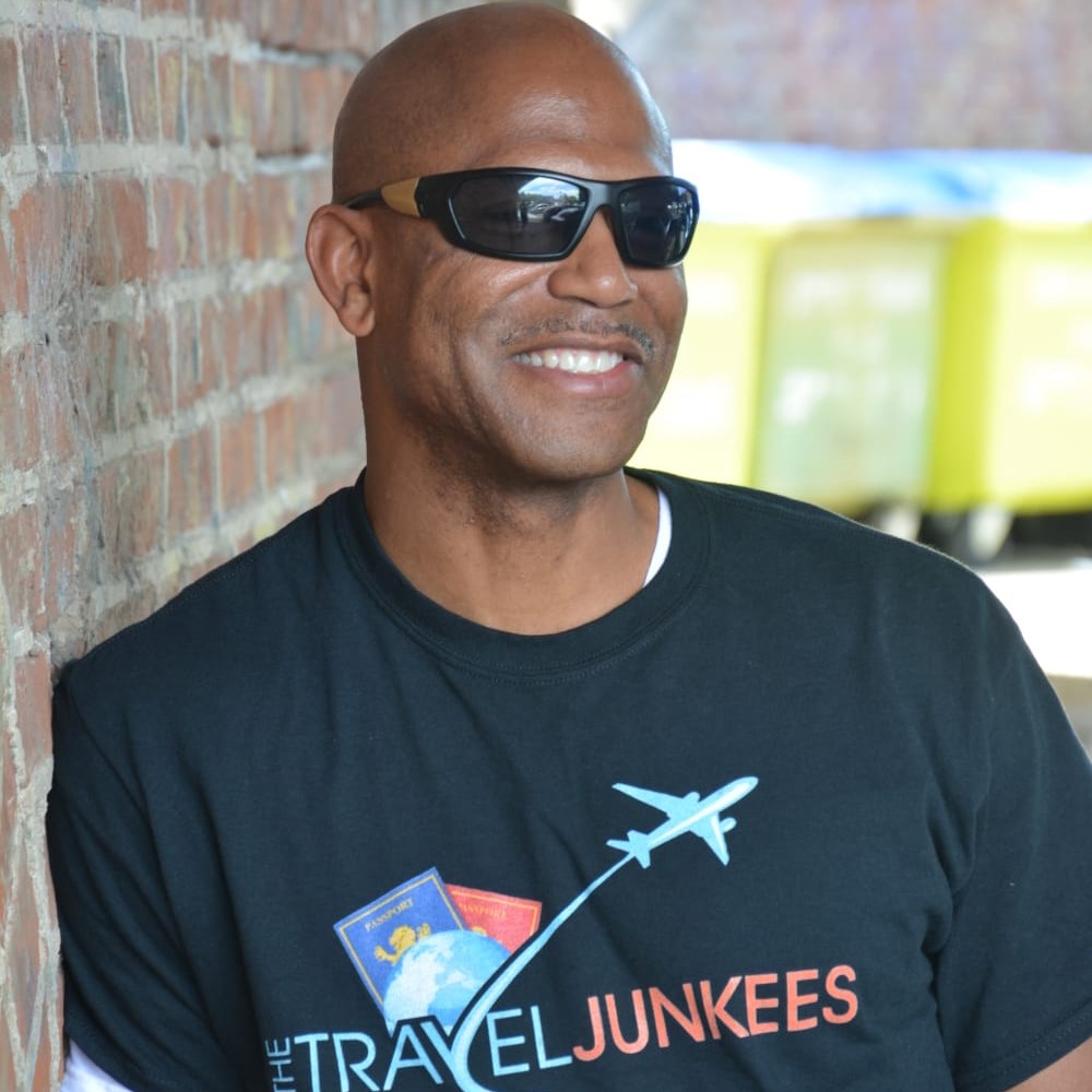 A man wearing the travel junkees t shirt with sunglasses